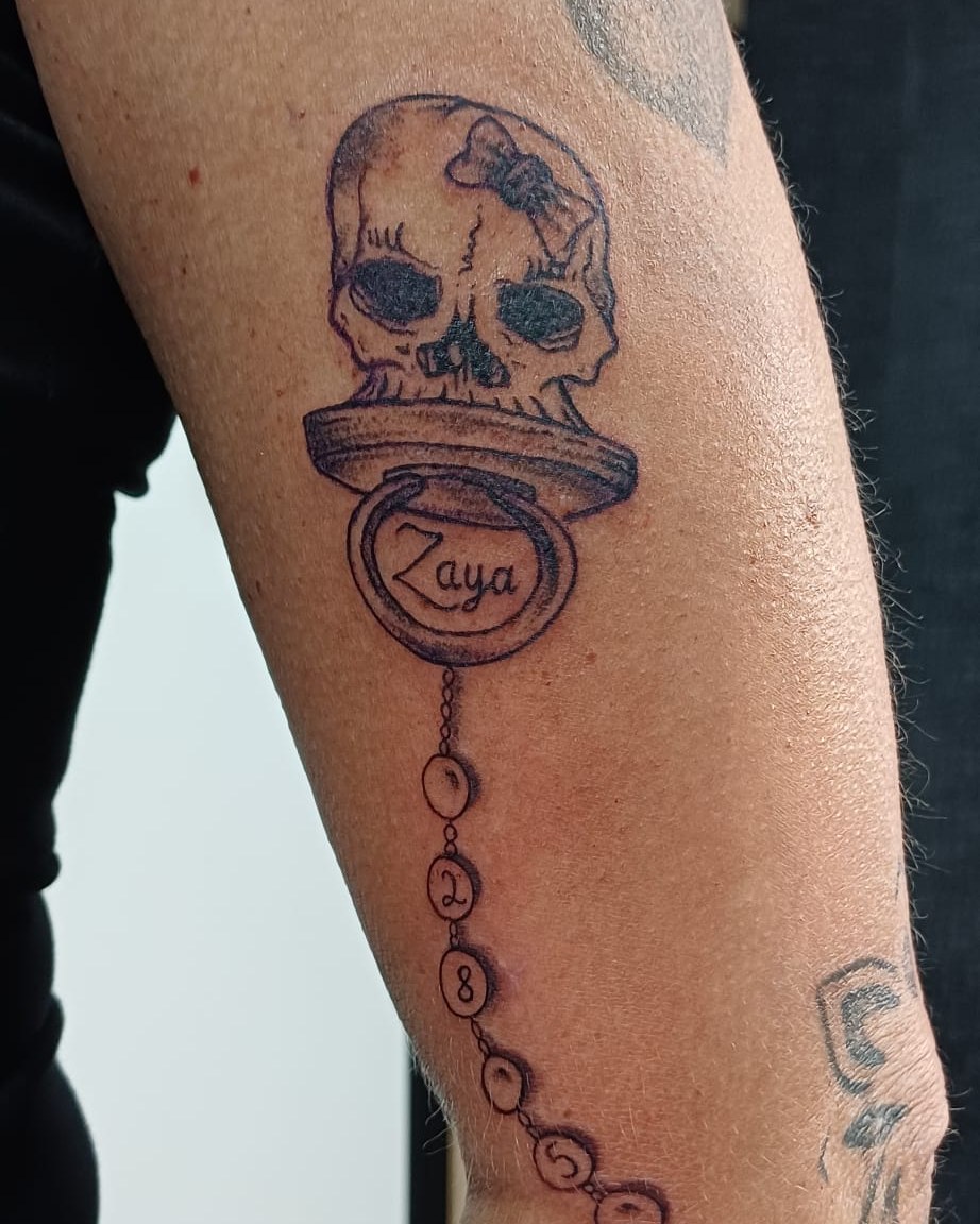 Doodshoofd met speen en kralenketting op een arm