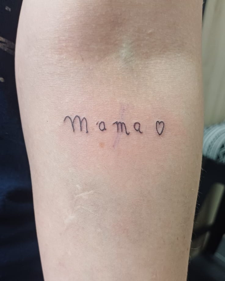 Het woord Mama met een hartje in fijne lijnen op een onderarm
